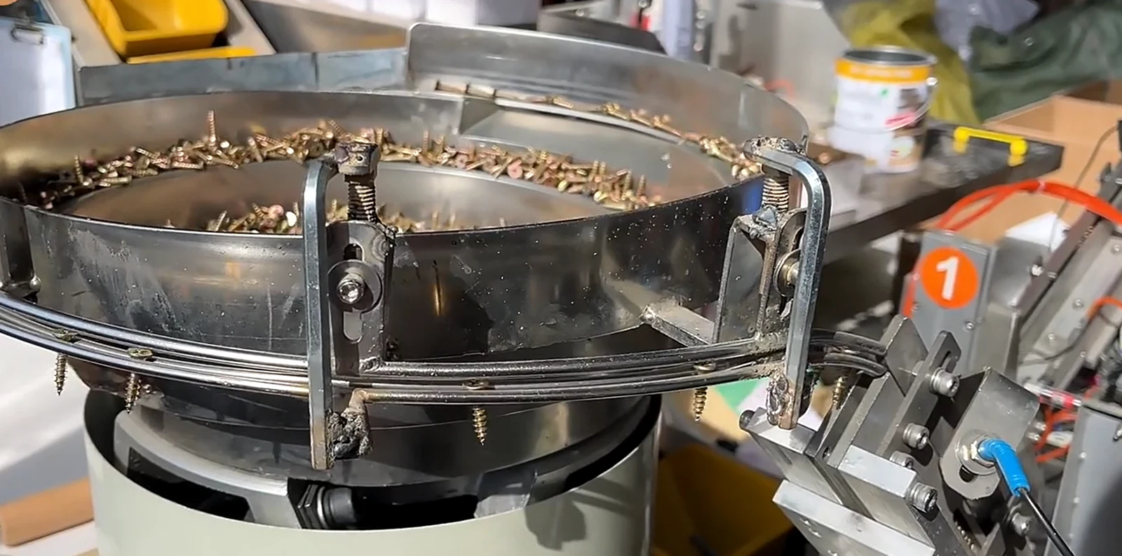 Metal fasteners in a vibratory feeder at a cat tree component workshop