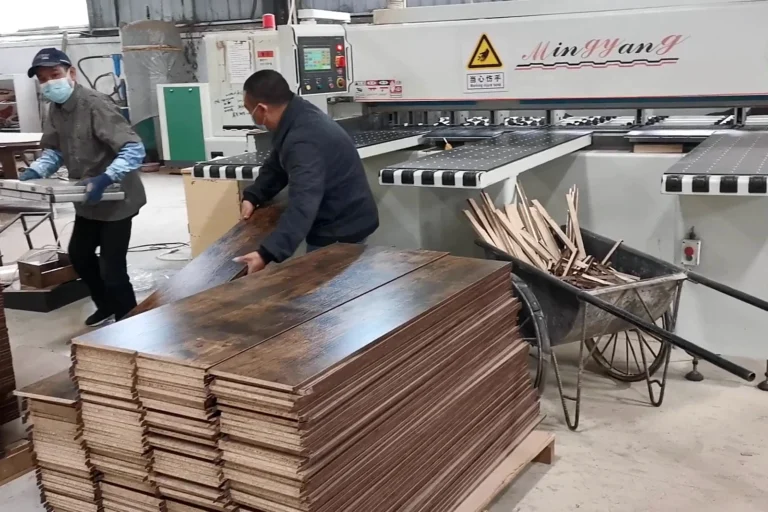 Two workers handling a batch of processed furniture panels