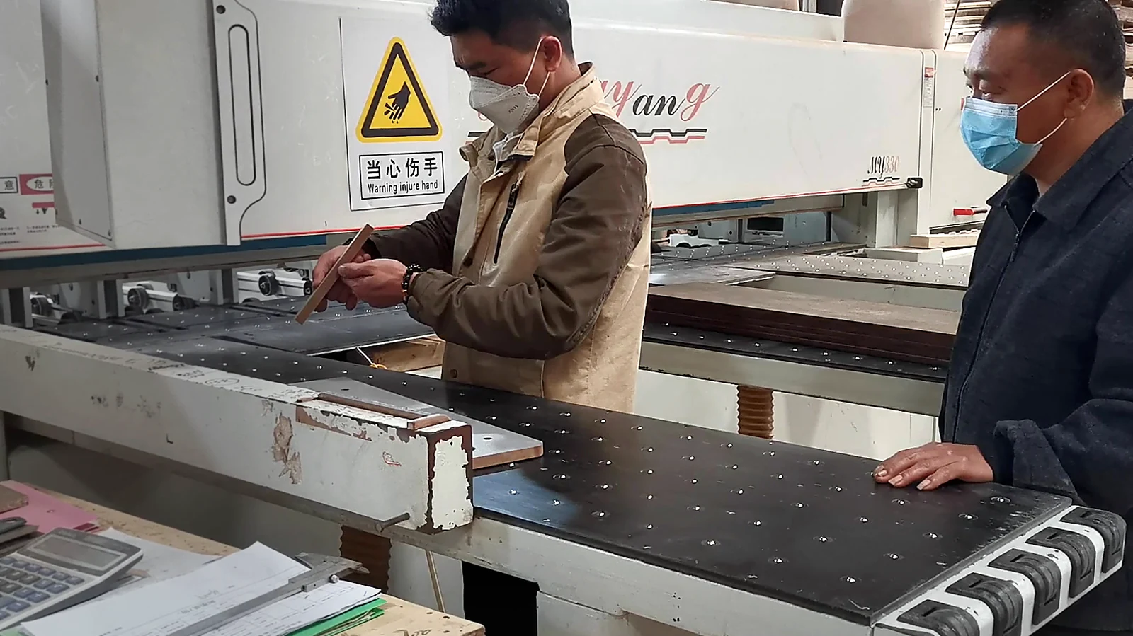 Two workers checking hole positions on a processed furniture panel