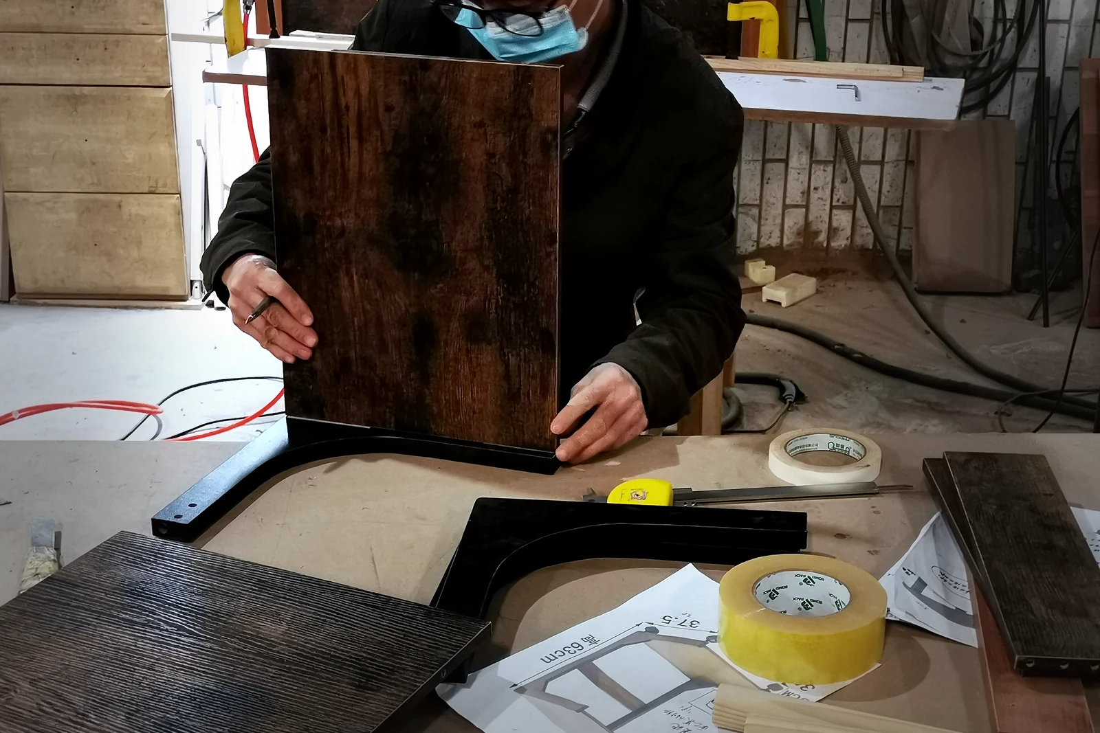 Worker checking the fit between a wood panel and a metal furniture frame