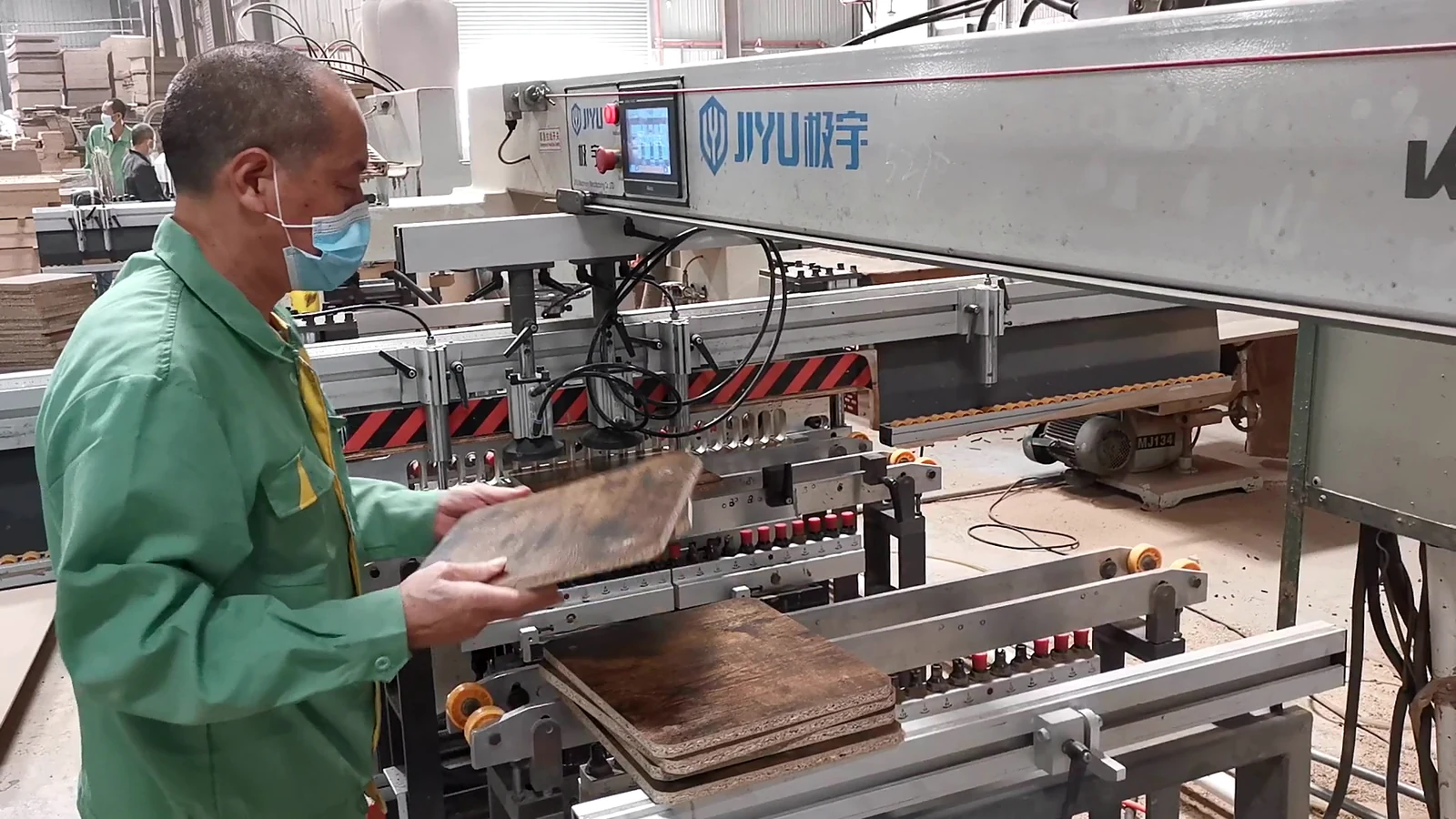 Operator visually checking a furniture panel before machine feeding